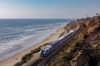 Pacific Surfliner train traveling across the coast adjacent to coastal bluffs and ocean