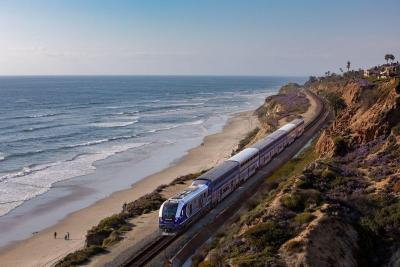 Pacific Surfliner train traveling across the coast adjacent to coastal bluffs and ocean